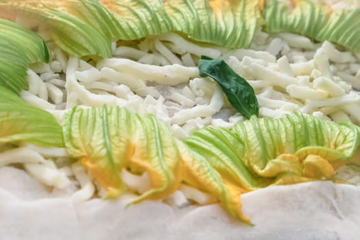 Closeup of raw pizza to bake, with mozzarella and zucchini. Vegetarian food.