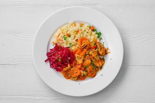 Top view of plate with beef goulash, rice with peas and beetroot salad