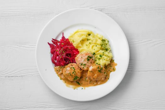 Top view of plate with meatballs, mashed potato and beetroot salad