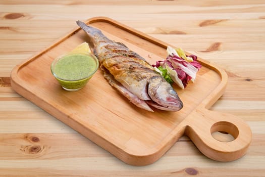 Whole fried fish on wooden board