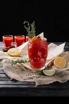 Selective focus composition with vodka and tomato juice cocktail served with  citrus and rosemary on rough paper and fabric over the wooden table