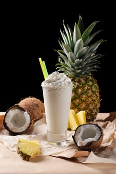 Selective focus composition with coconut cocktail served with  pineapple and coconuts on rough paper over the wooden table