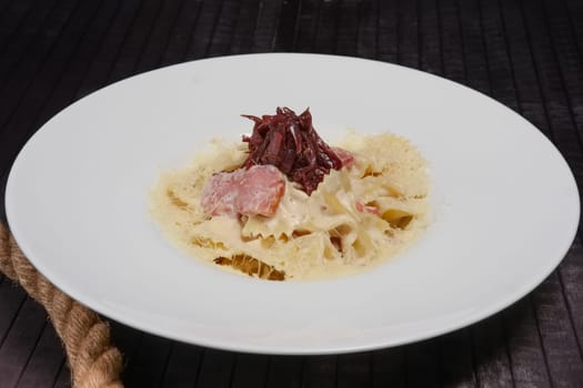 Big plate of pasta with ham, pickled onion and cheese