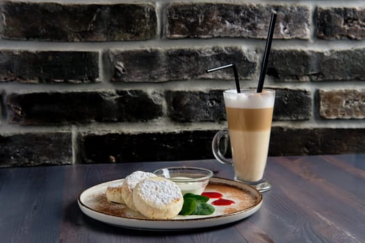 Traditional breakfast with cottage cheese pancake with sour cream, juice and latte