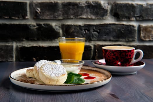 Traditional breakfast with cottage cheese pancake with sour cream, juice and latte