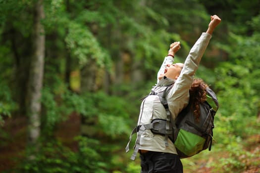 Hiker excited raising arms celebrating vacation in a forest