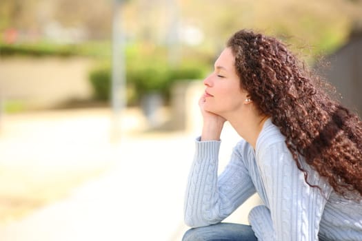 Side view portrait of a woman resting and relaxing with eyes closed sitting in a park