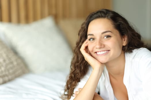 Portrait of a beautiful woman with perfect smile posing on a bed in a bedroom