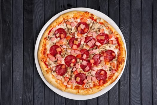 Top view of pizza with sausage, ham and tomato