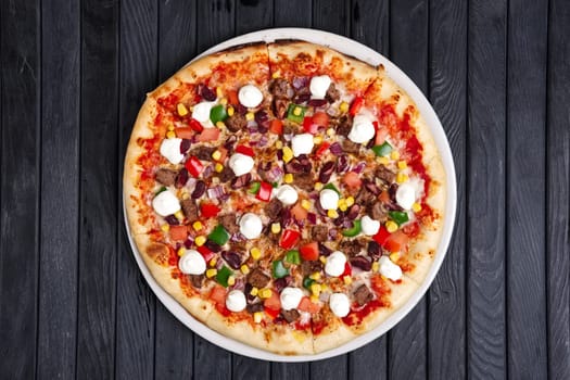 Top view of pizza with beef, feta cheese, bell pepper, corn and onion