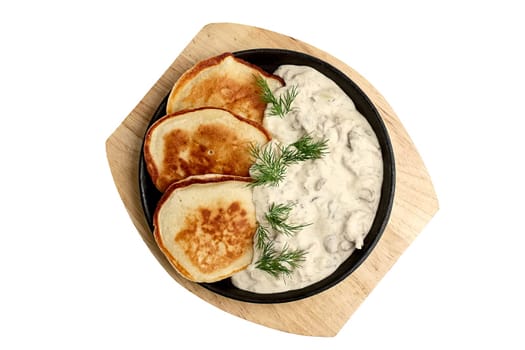 Flapjack with mushroom sauce on wooden plate. Top view.