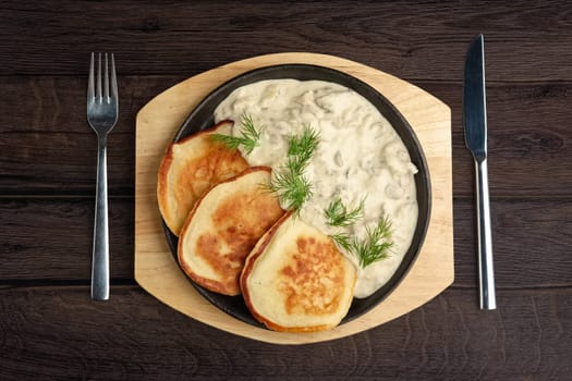 Flapjack with mushroom sauce on wooden plate. Top view.