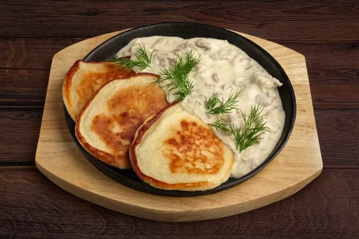 Flapjack with mushroom sauce on wooden plate. Top view.