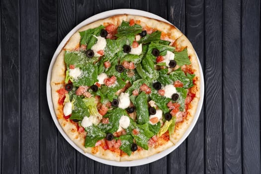 Top view of pizza with ham, feta cheese, anchovy and lettuce salad