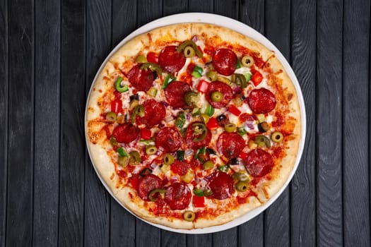 Top view of pizza with chili jalapeno, bell pepper, sausage and onion