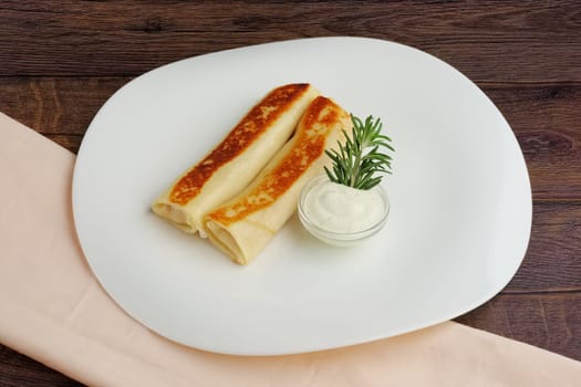 pancakes in roll with carrot and sauce on wooden table
