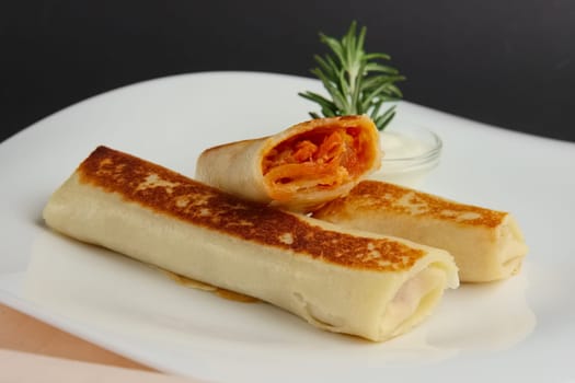 pancakes in roll with carrot and sauce on wooden table