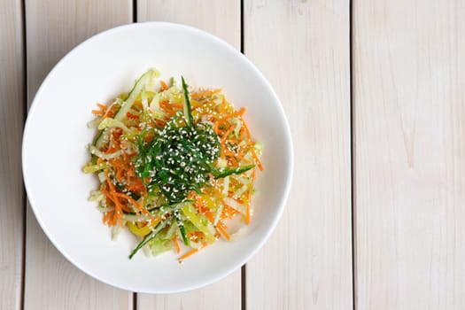 Salad with fresh cucumber, pepper, cabbage, carrot, seaweed and sesame