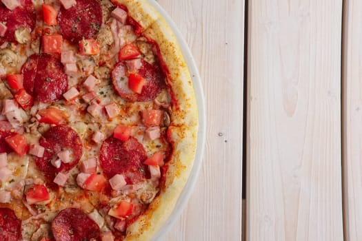 Freshly baked pizza with sausage and pieces of ham