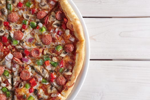 Pizza with sausage, ham, tomato, zucchini and paprika