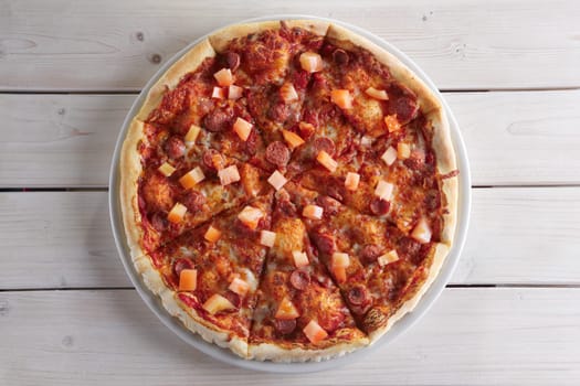 Pizza with sausage, ham, tomato, zucchini and paprika