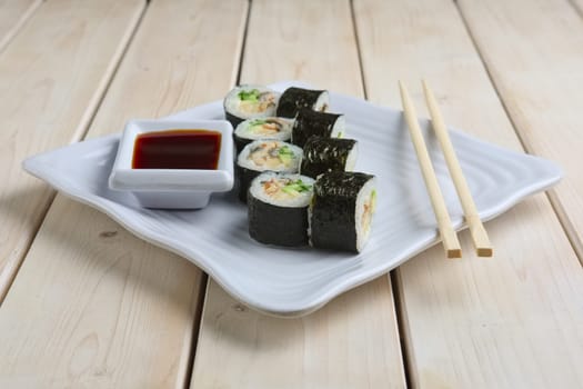 Set of rolls with salmon, avocado and cucumber on plate with soy sauce and hashi