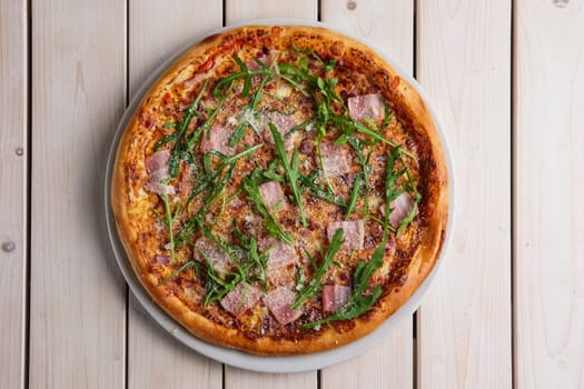 Pizza with bacon, bell pepper, onion and arugula