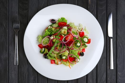 Salad with feta cheese rolled in cucumber slices with tomato and red onion