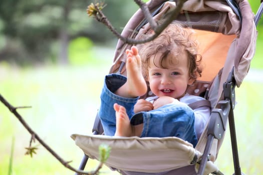 Portrait of baby boy sitting in his stroller while outdoor.