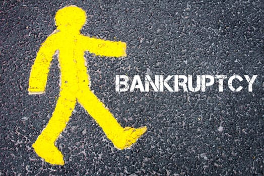Yellow pedestrian figure on the road walking towards BANKRUPTCY. Conceptual image with Text message over asphalt background.