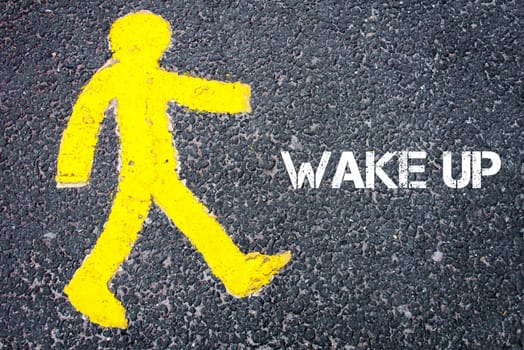 Yellow pedestrian figure on the road walking towards WAKE UP. Conceptual image with Text message over asphalt background.