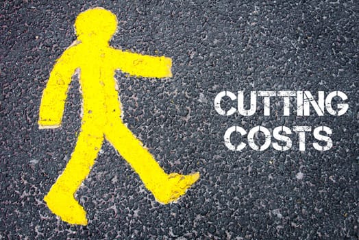 Yellow pedestrian figure on the road walking towards  CUTTING COSTS. Conceptual image with Text message over asphalt background.