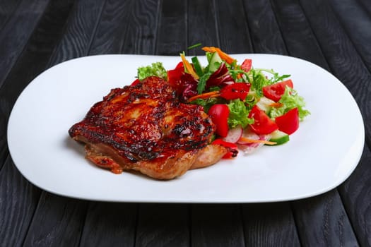 Juicy and crispy chopped pork fried on grill with fresh vegetables (red cabbage, tomato, cucumber, carrot and bell pepper)