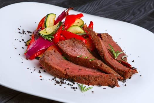 Roasted beef cutted on slices with grilled bell pepper, zucchini, onion and fresh rosemary