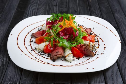 Salad with beef, feta cheese, tomato, red cabbage, carrot and radish dripped with wine vinegar