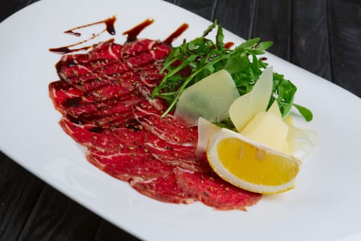 Beef carpaccio with cheese, white bread toasts and lemon
