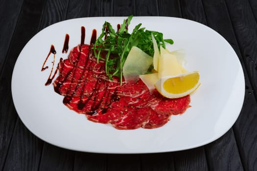 Beef carpaccio with cheese, white bread toasts and lemon