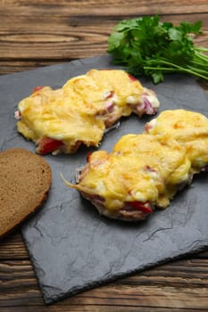 Baked in oven meat with mushrooms, tomato and cheese, servet on stone plate
