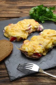 Baked in oven meat with mushrooms, tomato and cheese, servet on stone plate