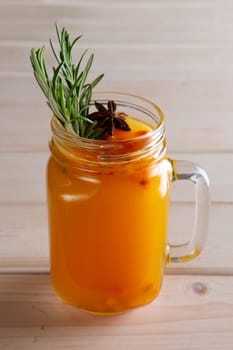 Cup of sea buckthorn tea with citrus, cinnamon and rosemary