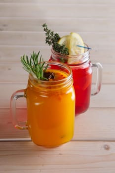 Two cups of cranberry tea and sea buckthorn tea with citrus, cinnamon and rosemary