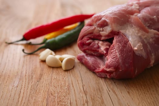 Fresh pork shoulder ready for baking with hot chilly and jalapeno pepper, garlic and lemon. Shallow depth of field photo.
