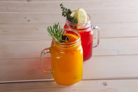 Two cups of cranberry tea and sea buckthorn tea with citrus, cinnamon and rosemary