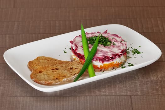 Russian Shuba Salad with Beetroot, Potatoes, Carrots and Herring Studio Photo. Russian herring salad on a white plate for holiday.