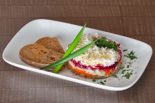 Traditional russian salad with beet, carrot, herring and onion