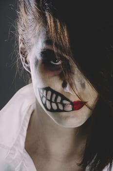 Scary woman with halloween makeup mask on her face.