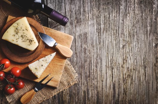 Top view of red wine and cheese on rustic wooden background with copyspace. French cuisine product..