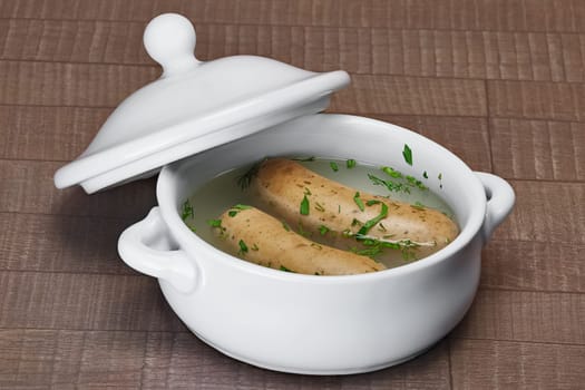 Homemade sausage boiled with dill and spice on wooden table in pot