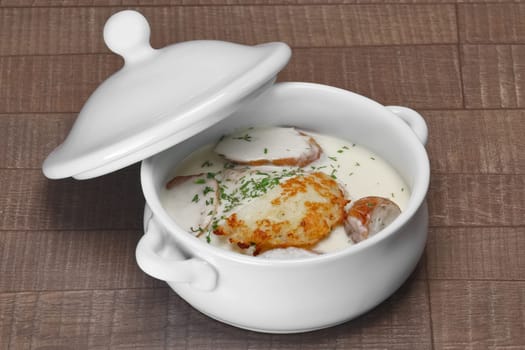 White bowl with machanka and potato pancakes on wooden table