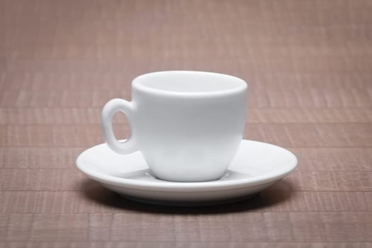 Clean and empty ceramic cup for espresso with saucer on wooden table.